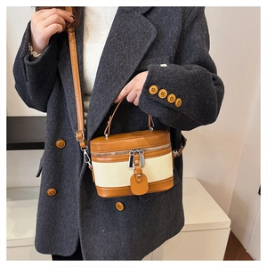 Close-up of a retro patchwork box bag worn with a grey coat for a stylish look