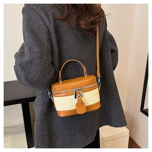 Detail of a vintage boxy crossbody bag featuring brown leather and beige canvas stitching