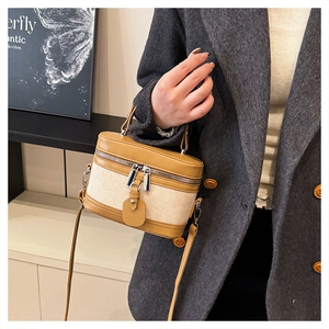 Close-up of retro box bag in tan leather and beige canvas worn with a grey wool coat