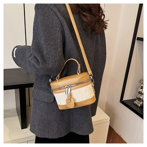 Brown leather and canvas bucket bag shown on a model wearing a grey coat