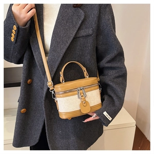 Detail of vintage box bag with leather and canvas contrast on a gray blazer