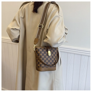 Detail of vintage bucket bag featuring monogram print and golden metal clasp on a beige coat