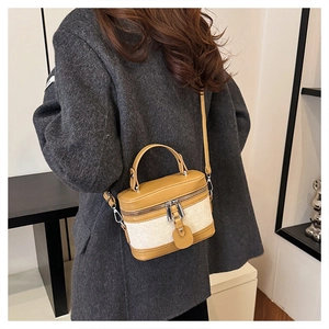 Detail of vintage box-style crossbody bag in yellow leather and canvas on model