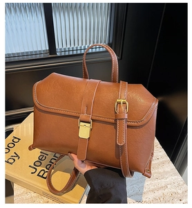 Close-up of vintage brown leather handbag with gold metal clasp and stitch detail