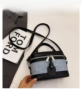 Close-up of structured contrast bag featuring blue denim and black leather with dual zippers