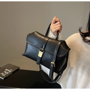 Detail of black retro leather handbag featuring contrast white stitching and buckle closure