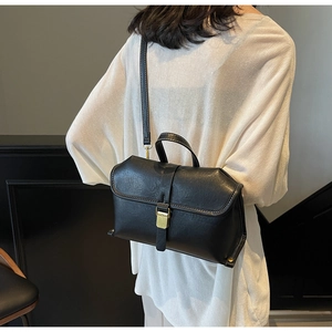 Detail of classic black leather handbag with gold metal clasp and white contrast stitching