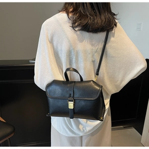 Detail of vintage black crossbody bag with gold buckle and contrast stitching on shoulder