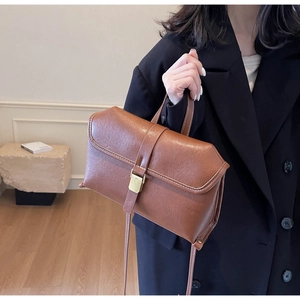 Close-up of vintage brown leather handbag featuring gold metal clasp and white stitching