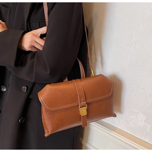 Detailed view of a brown leather handbag with a vintage gold buckle and strap