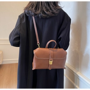 Detailed shot of brown leather handbag with contrast stitching and gold metal clasp