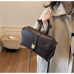 Detail of dark brown leather handbag featuring white stitching and gold buckle