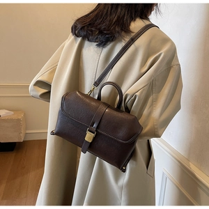 Detail of dark brown vintage crossbody bag featuring buckle closure and matte leather texture