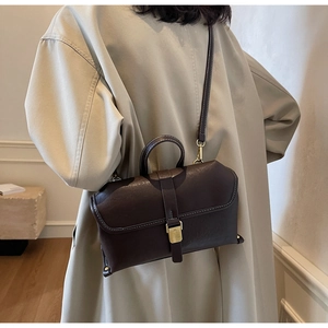 Detail of dark brown retro leather handbag with vintage metal clasp and top handle