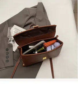 Detail of spacious interior storage for phone, umbrella, and wallet in vintage brown bag