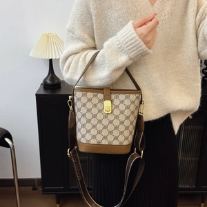 Chic beige monogram bucket bag with brown leather trim and wide jacquard strap