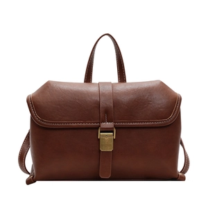 Vintage brown leather crossbody bag with white stitching and brass lock on white background