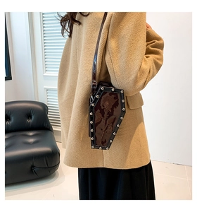 Gothic coffin-shaped shoulder bag featuring rose embossing and silver studs worn by model