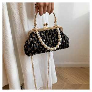 Detail of black pleated clutch with gold sequins, pearl handle and retro metal clasp