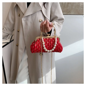 Detailed view of red pleated evening bag with pearl handle and vintage metal clasp