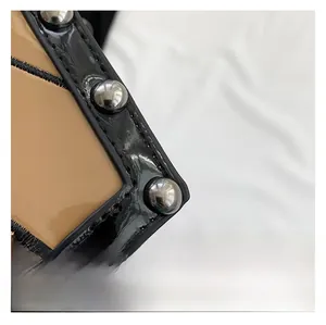 Detail of brown patent leather texture and silver rivets on the coffin shoulder bag