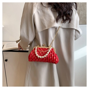 Detail of red pleated sequin shell bag with elegant pearl handle and gold chain strap