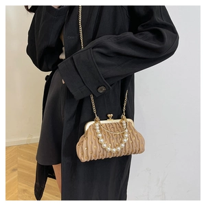 Detail of pleated beige clutch bag featuring pearl handle and gold chain strap