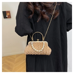 Detail of pleated sequin clutch with pearl handle and chain strap shown on a model