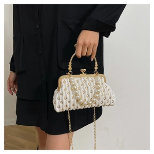 Detail of white pleated clutch with gold heart embroidery, pearl handle and metal clasp