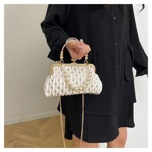 Detail of white pleated clutch with gold hearts, pearl handle and metal chain
