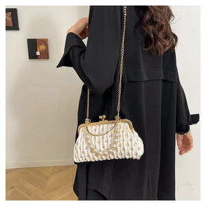 Detailed side view of pleated pearl white clutch bag with gold chain and handle on model