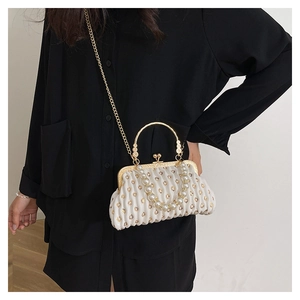 Detail view of white ruched clutch bag with heart sequins and pearl handle on black shirt