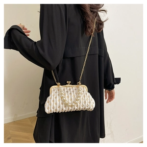 Close-up of white pleated shell bag featuring gold polka dots and pearl bead handle