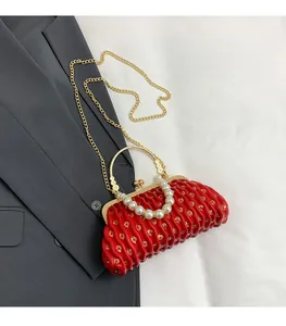 Close-up of red pleated clutch bag featuring pearl ring handle and gold sequin details