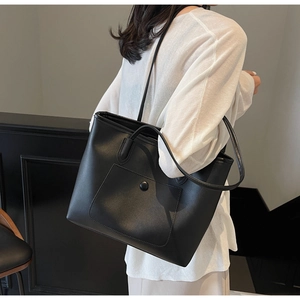 Close-up of black leather tote bag featuring a practical front pocket and textured finish