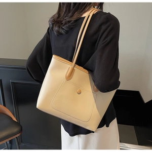 Detail view of large cream tote bag with dark brown leather trim and stylish front pocket