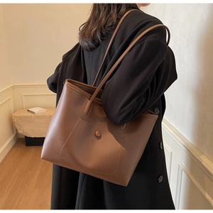 Detail of vintage brown leather tote bag showing large front pocket and circular buckle