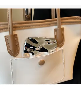 Close-up of contrast stitching on a cream tote bag with brown handles and a front pocket