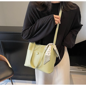 Detailansicht der hellgrünen Leder-Eimertasche mit dekorativem Seidentuch und Logoprägung
