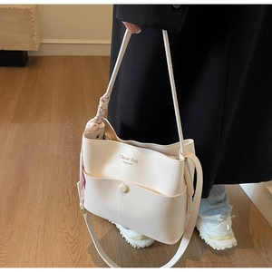 Detail der cremeweißen Beuteltasche mit floralem Seidentuch und Magnet-Fronttasche