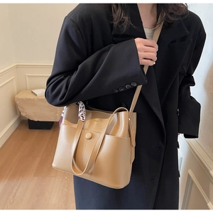 Details einer Retro-Eimertasche aus Leder mit Schal am Griff und Schultergurt