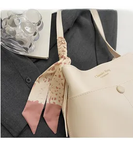 Detail der cremefarbenen Beuteltasche mit rosa Leoparden-Seidenschal am Griff und Logo