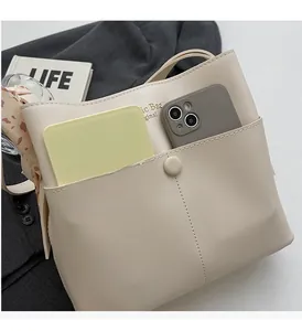 Detailansicht der beigen Eimer-Handtasche mit praktischem Frontfach für Smartphones