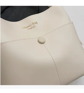 Detail der cremeweißen Beuteltasche mit Goldaufdruck und Magnetverschluss