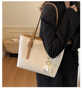 Detail of white PU leather tote bag featuring brown straps and a cute elephant charm