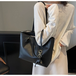 Detail view of black PU leather tote bag with fringe charm and Fashion Trend logo