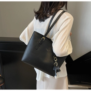 Detail of black faux leather tote bag with gold buckle and cute elephant charm
