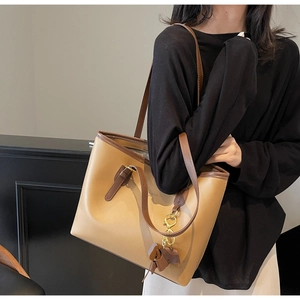 Close-up of elephant gray tote bag with contrasting brown handles and bow charm detail