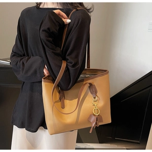 Detail of two-tone brown tote bag featuring an elephant charm and spacious PU leather design