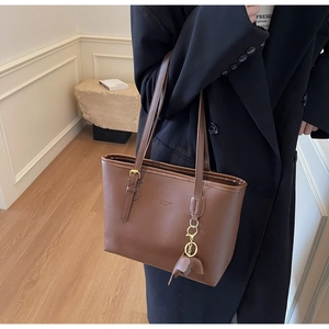 Detail of vintage brown leather tote bag with adjustable buckle strap and logo embossing
